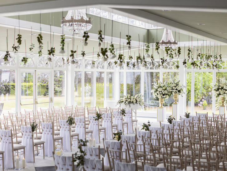 Wedding ceremony room with many windows, natural light and floral decor